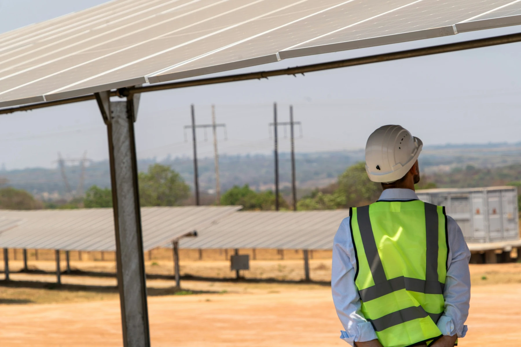 Technicien casqué observant une grande installation photovoltaïque au sol