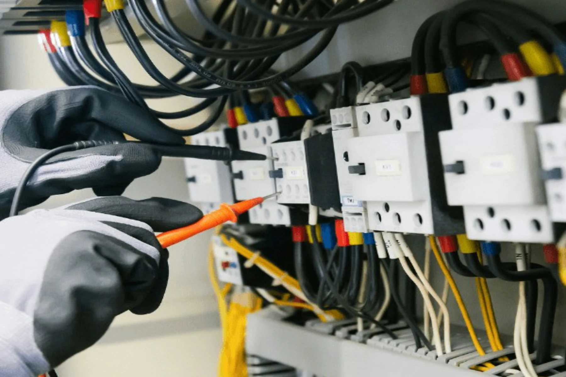 Électricien ganté contrôlant des connexions dans un coffret de protection