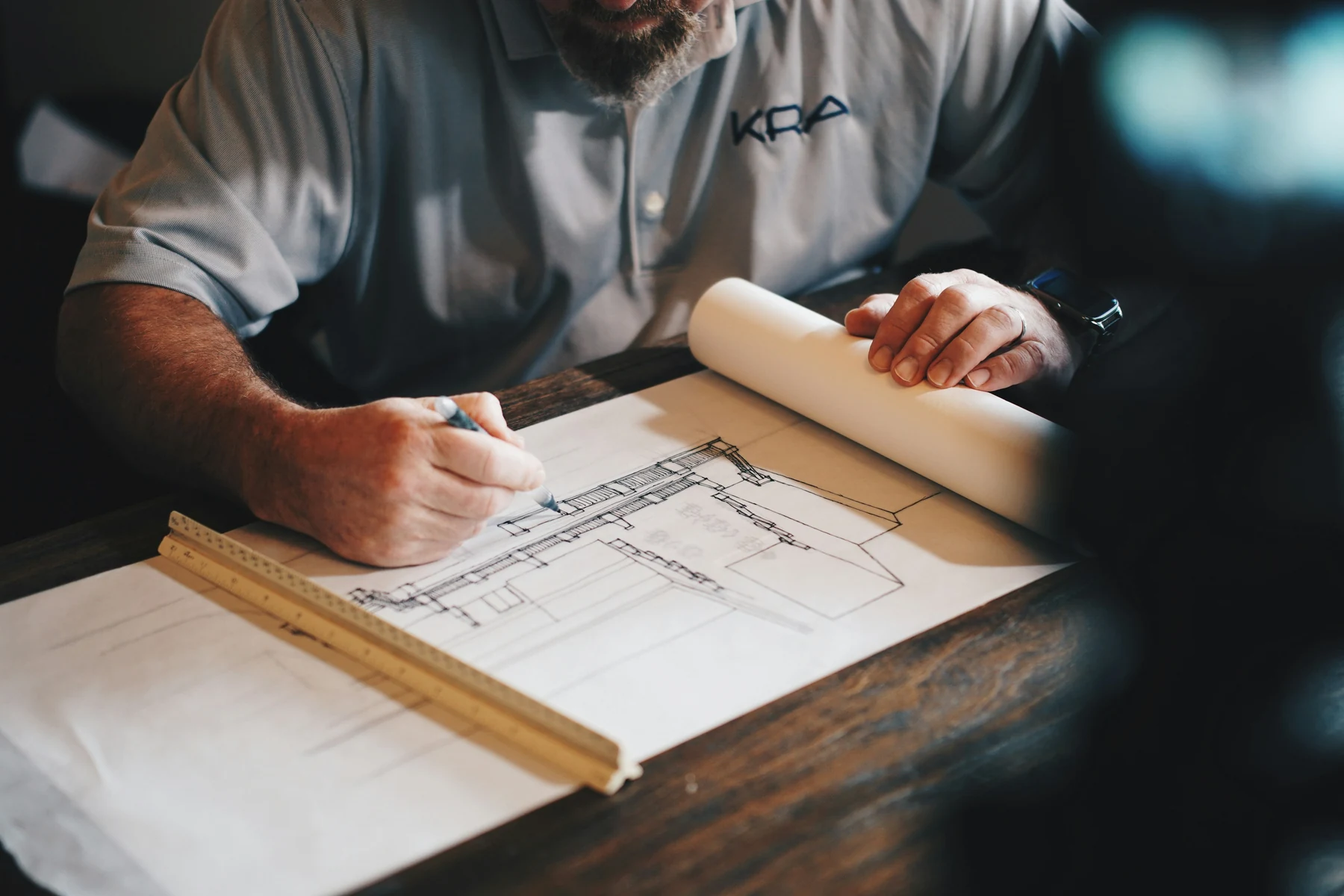 Professionnel annotant des plans techniques avec une règle et un crayon