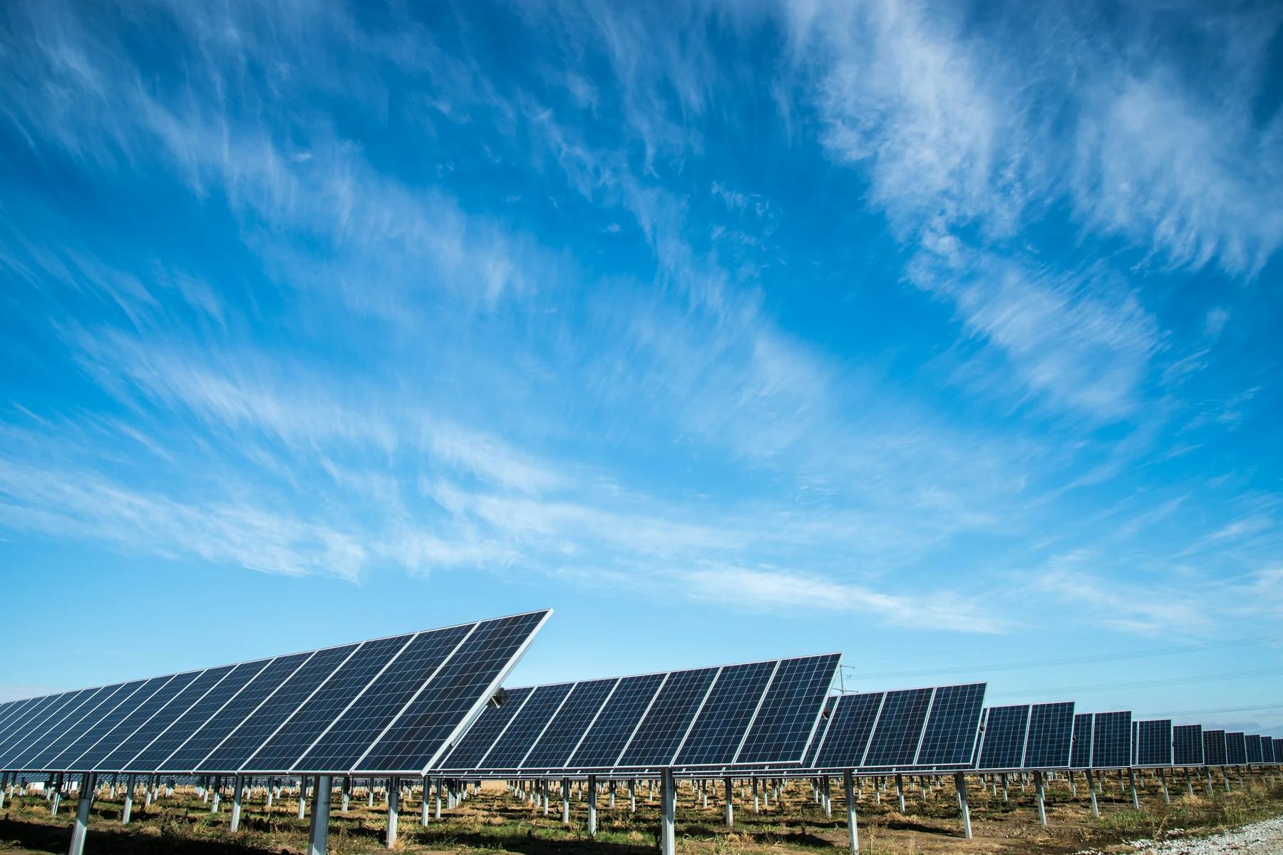 Alignement de panneaux photovoltaïques sous un vaste ciel dans un paysage rural